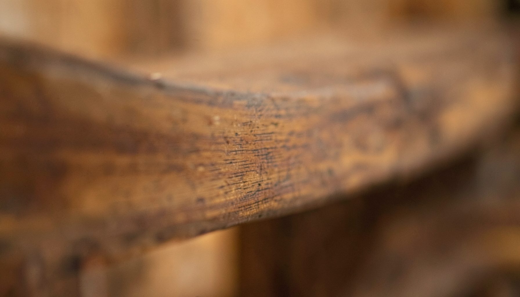 Soft-focus view of a wooden beam with subtle surface texture, warm amber and brown hues, calm and understated mood